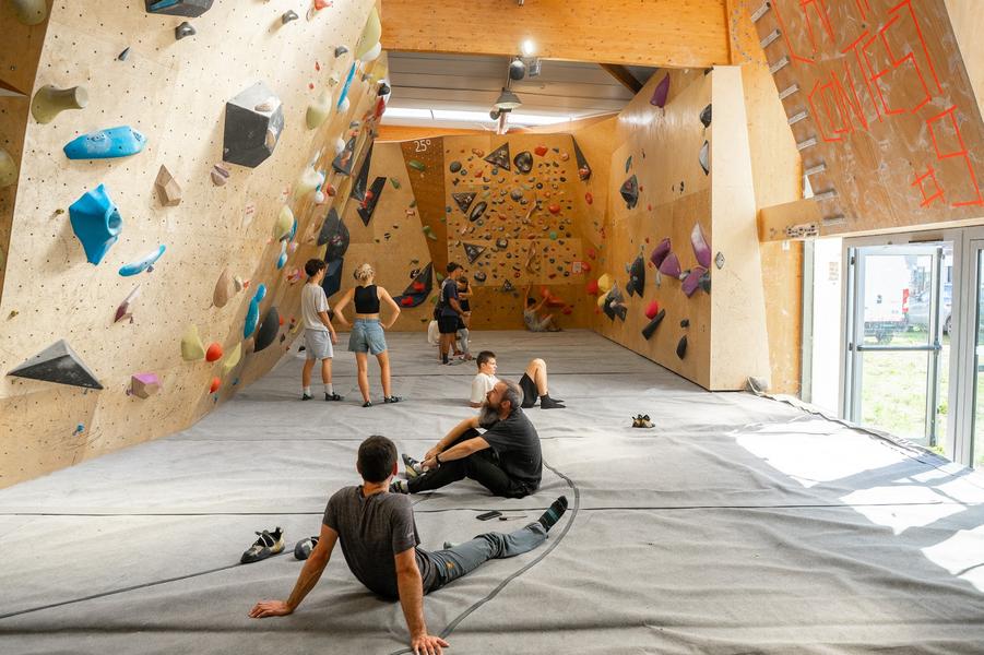 Des personnes sur les tapis au pied des murs d'escalade.