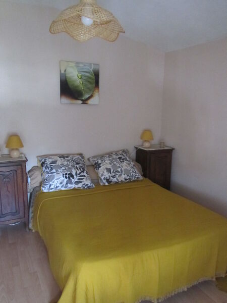Chambre avec tables de chevet, lit double et couverture jaune.