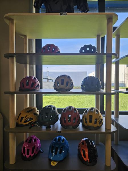 Une douzaine de casque de vélo de toutes les couleurs en magasin.