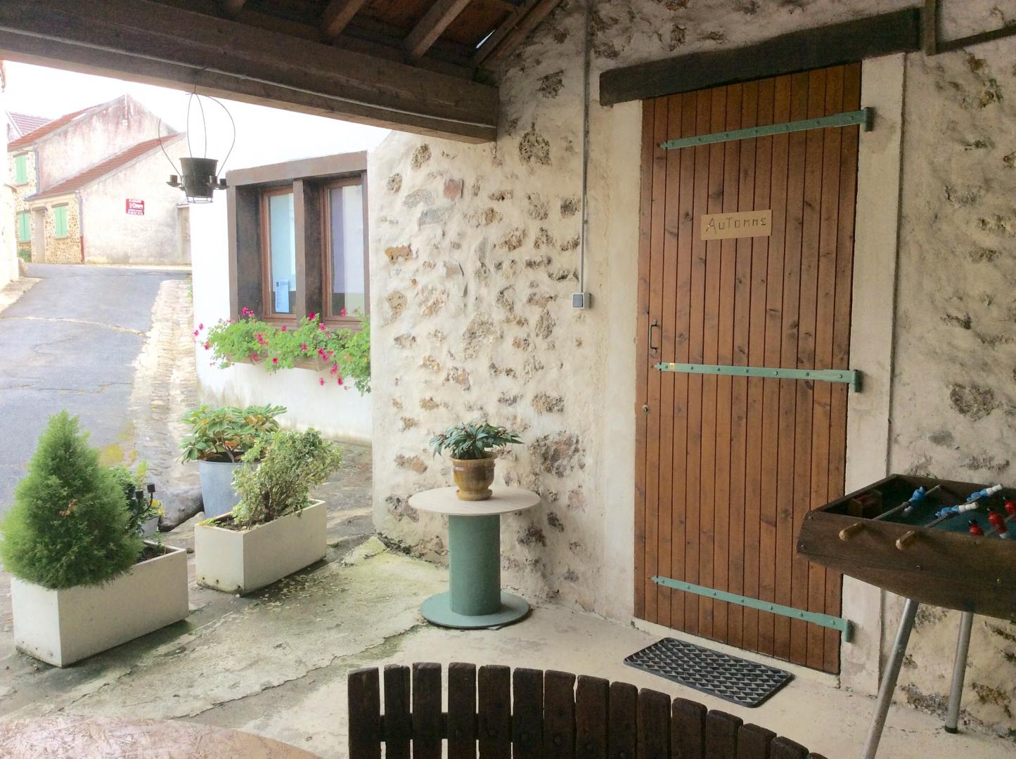 Entrée du gite AUTOMNE, terrasse couverte avec vue sur la cour fleurie