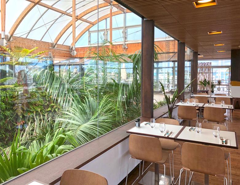 Des tables dressées dans la salle, donnant sur la serre de l'aquarium.