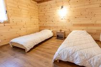 Chambre à coucher lumineuse avec 2 lits simples, ameublement bois, parquet au sol, fenêtre