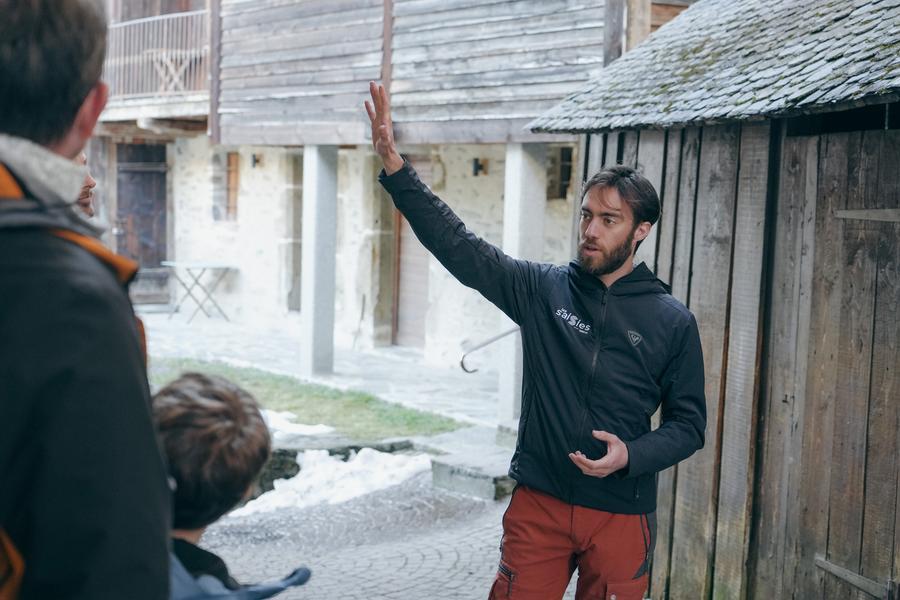 Le guide montre quelque chose sur le parvis de l'écomusée