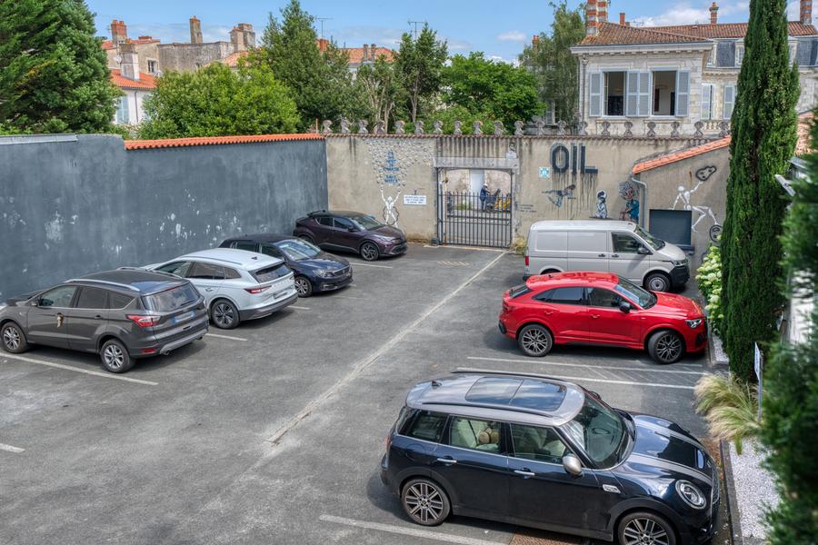 Le parking privé fermé de l'hôtel, avec une dizaine de places visibles, 7 voitures sont garées.