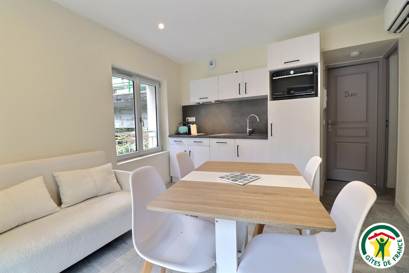 Pièce à vivre avec cuisine équipée, espace repas, canapé, TV