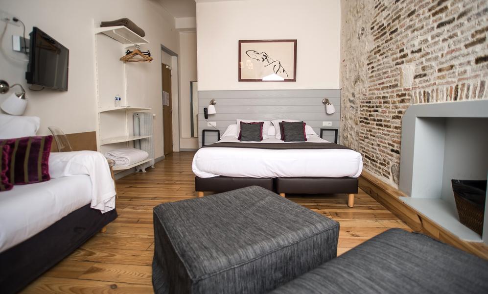 une chambre avec deux lits de 90 rassemblés en un lit double, des poufs, et un canapé.