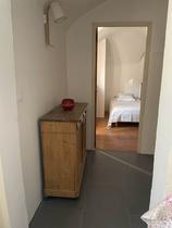 Couloir d'appartement avec ameublement bois, porte vers la chambre à coucher avec lit simple