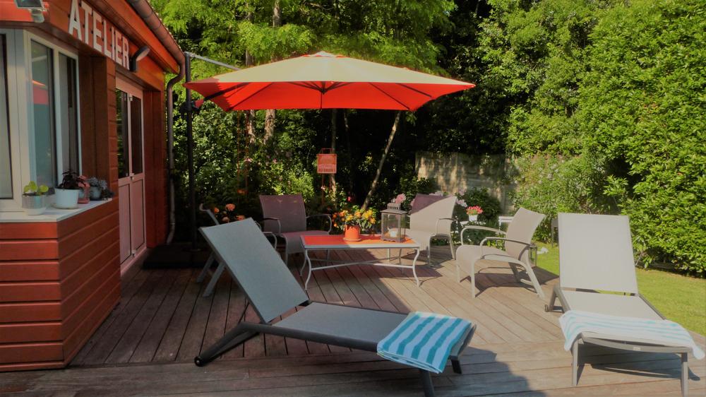 Un salon de jardin, 2 bains de soleil et un parasol sur pied sur la terrasse.