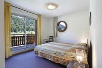 Apartment bedroom with double bed, porthole window, French doors opening onto a balcony