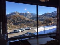 Pièce lumineuse donnant sur l'extérieur, ameublement bois, grande fenêtre, vue sur les montagnes enneigées