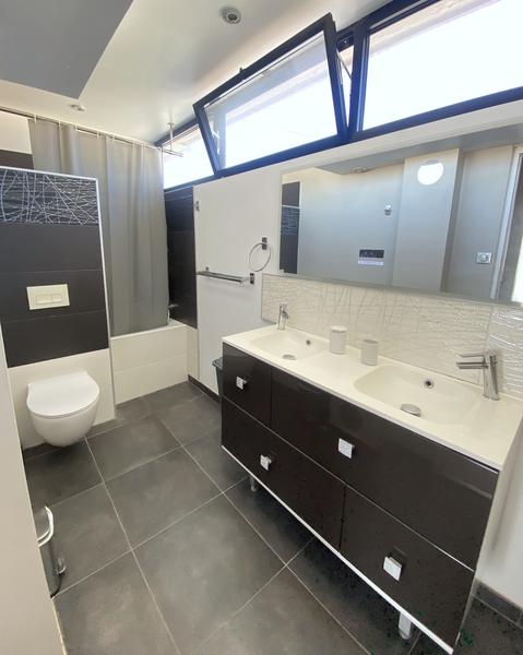 Une salle de bain avec lavabo double vasque, miroir, toilette, baignoire.