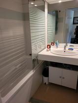 Salle de bains avec baignoire, évier, miroir et meuble de rangement