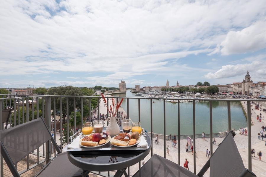 Deux chaises et une table avec petit-déjeuner sur un balcon, avec vue sur le vieux-port.