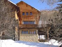 Vue extérieure du chalet en bois et pierre sur 3 étages, avec terrasse en bois