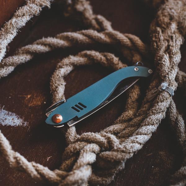 Un couteau "Tibur" replié, posé sur une corde de bateau.
