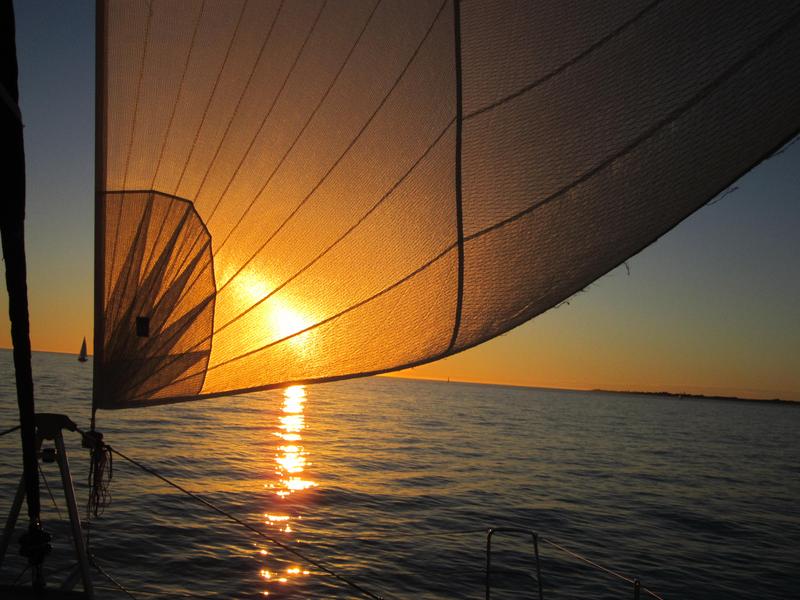 Vue sur un coucher de soleil depuis un voilier en mer.