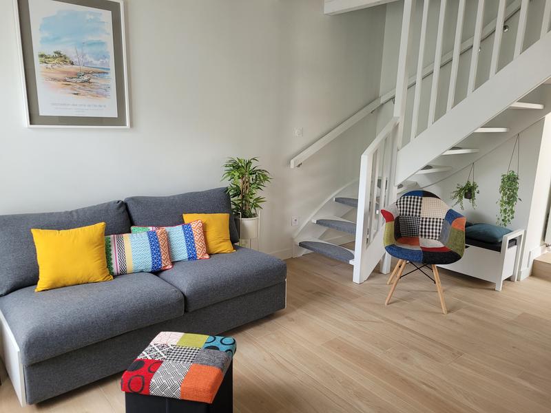 Un canapé convertible, une chaise, un escalier menant vers l'étage.