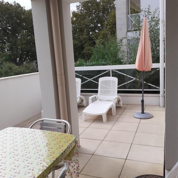 Balcon avec table et chaises, et deux bains de soleil.