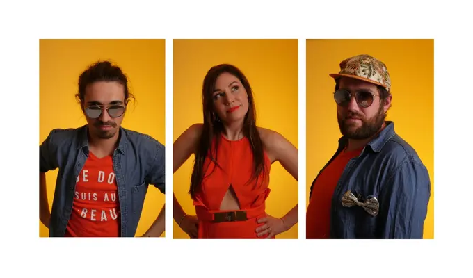 Three portraits of musicians are presented side by side against a bright yellow background. In the center, a woman in a red dress poses between two men wearing denim shirts and sunglasses, creating a colorful and stylish ensemble.