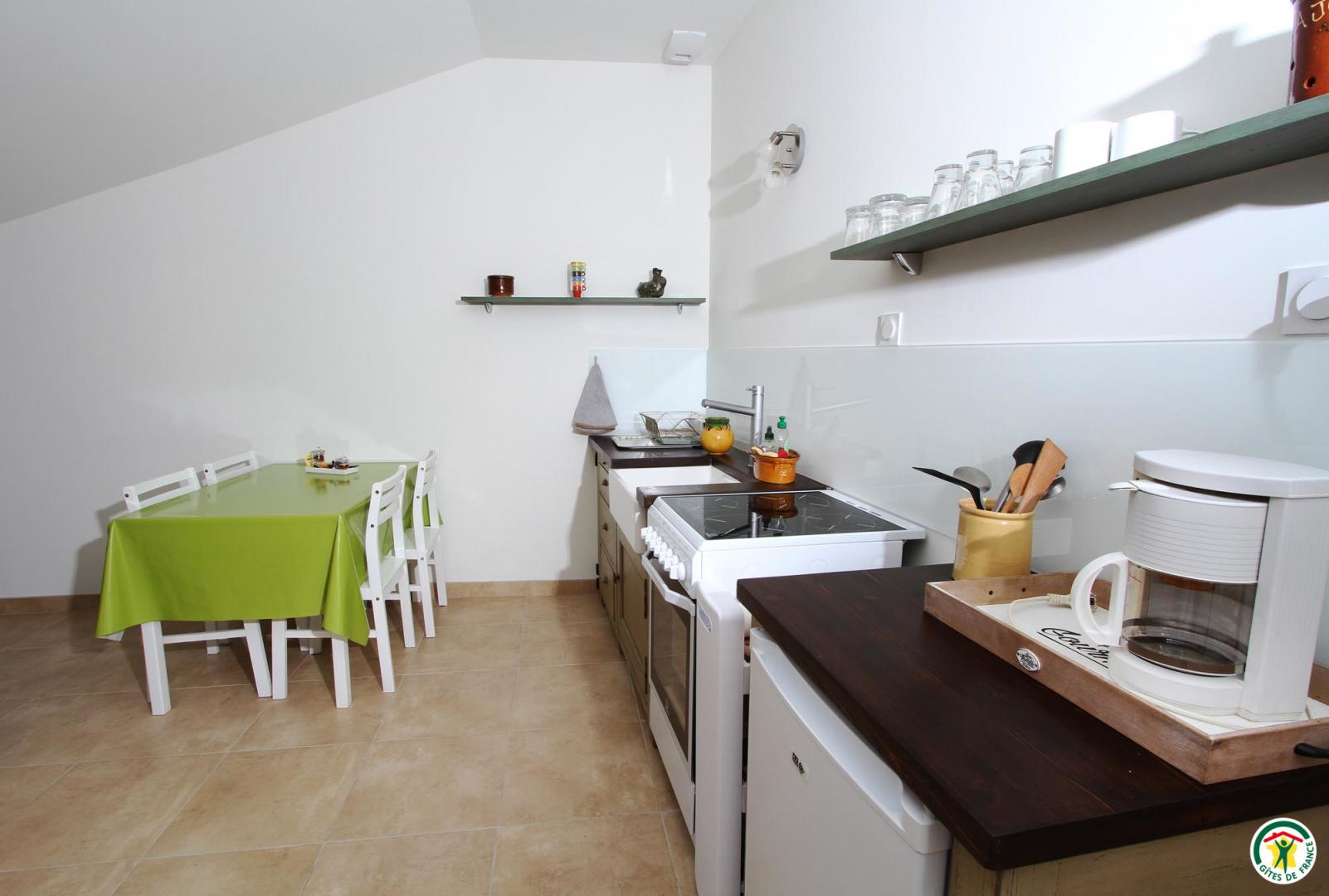 Espace repas avec grille pain, bouilloire, machine a café filtre, cuisinière et four électrique
