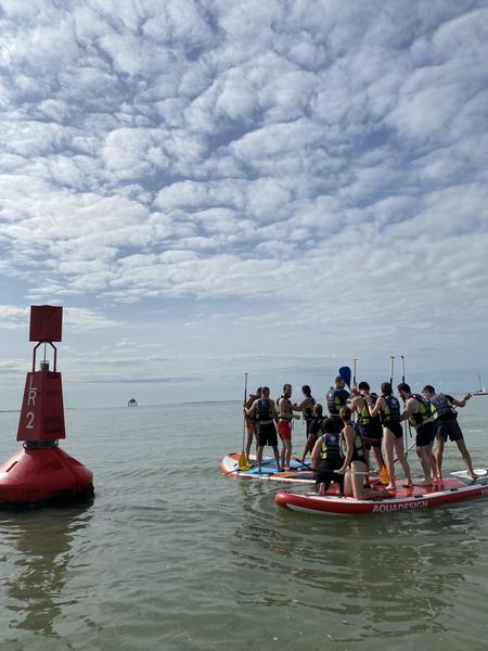Une dizaine de personnes debout sur deux paddle géants.