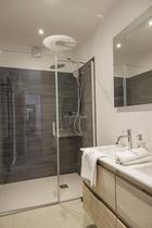 Salle de bains, grand bac à douche, évier, parquet au sol et ameublement bois