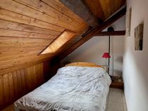 Chambre à coucher sous combles avec lit double, carrelage, ameublement bois