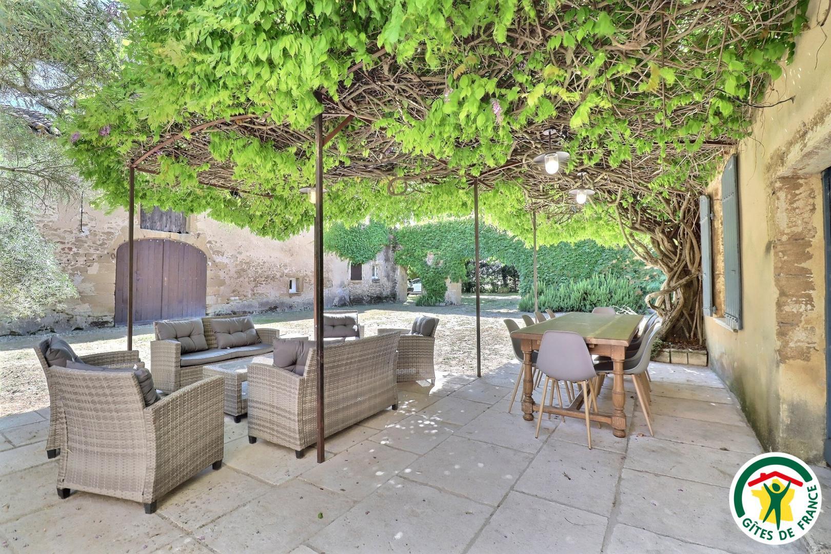 Terrasse privative au gîte sous la glycine, pas de vis à vis. Salon détente et coin repas, barbecue