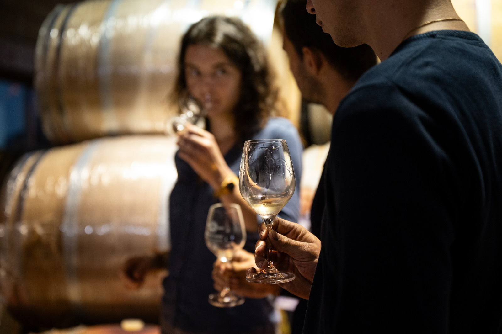 Personnes en train de déguster un vin blanc dans la cave d'un domaine viticole