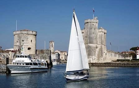 Un voilier et un gros navire face aux tours de la Rochelle.