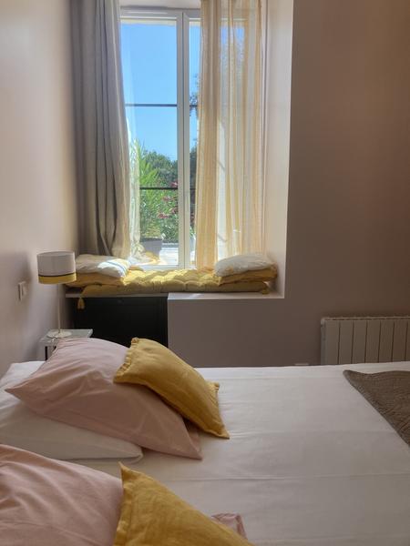 Chambre avec un lit double, un coussin de sol sur le rebord de la fenêtre.