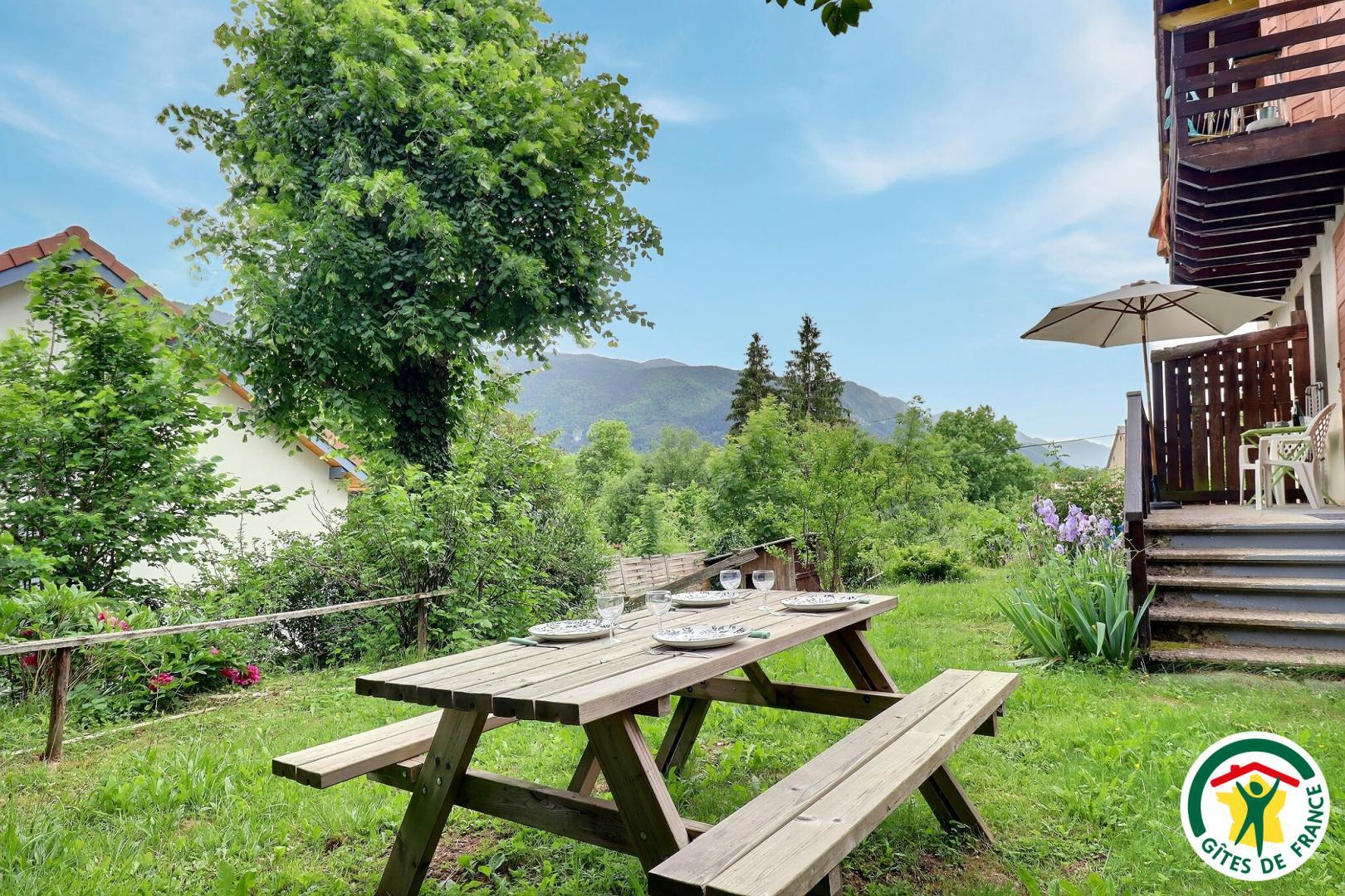 L'extérieur du gîte avec table, bancs, vue montagne