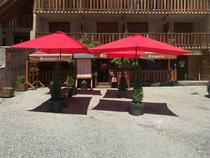 Vue de la terrasse de la crêperie en été, terrasse avec parasols et bancs