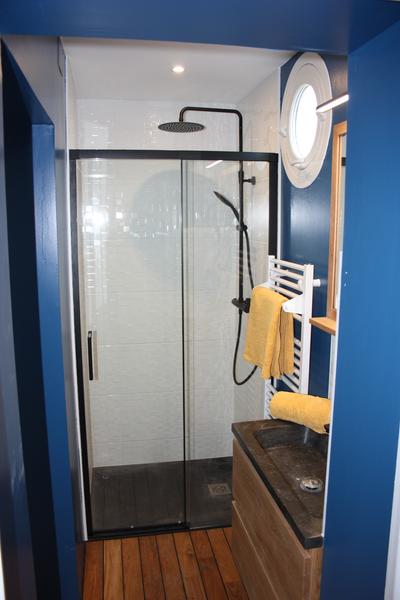 Une salle d'eau avec douche à l'italienne, vasque et sèche serviette.