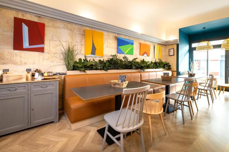 La salle de petit-déjeuner avec des tables, des chaises et deux grandes banquettes.