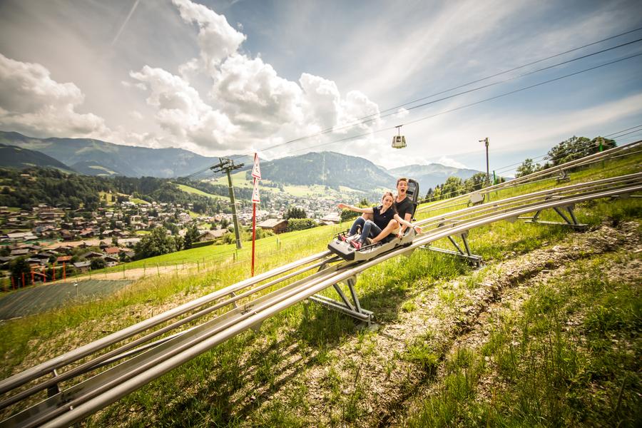 Enfant sur luge avec en fond télécabine Jaillet et village Megève Enfant sur luge avec en fond télécabine Jaillet et village Megève