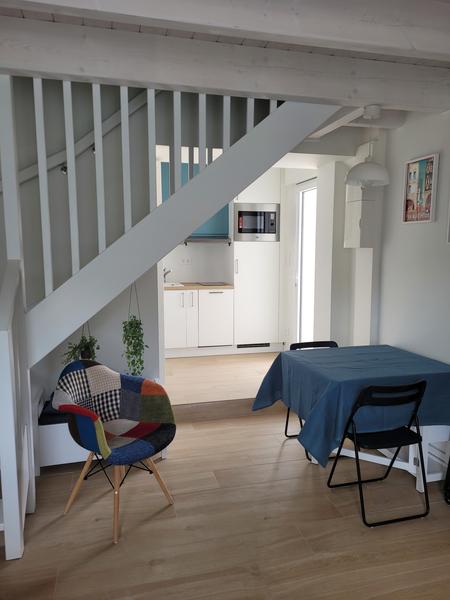 Une chaise, une table avec deux chaises métalliques, la pièce donne sur la cuisine.
