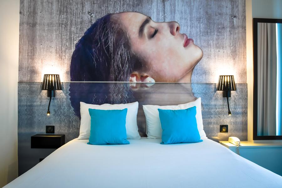 Un lit double, une peinture d'un visage de femme sur le mur.