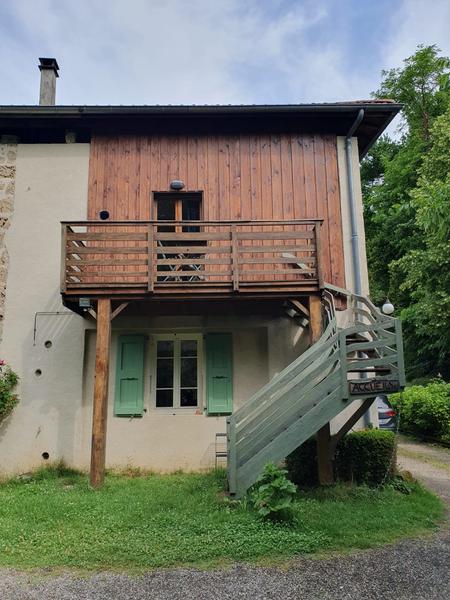 Gîte indépendant avec balcon en bois, niché dans un écrin de verdure.