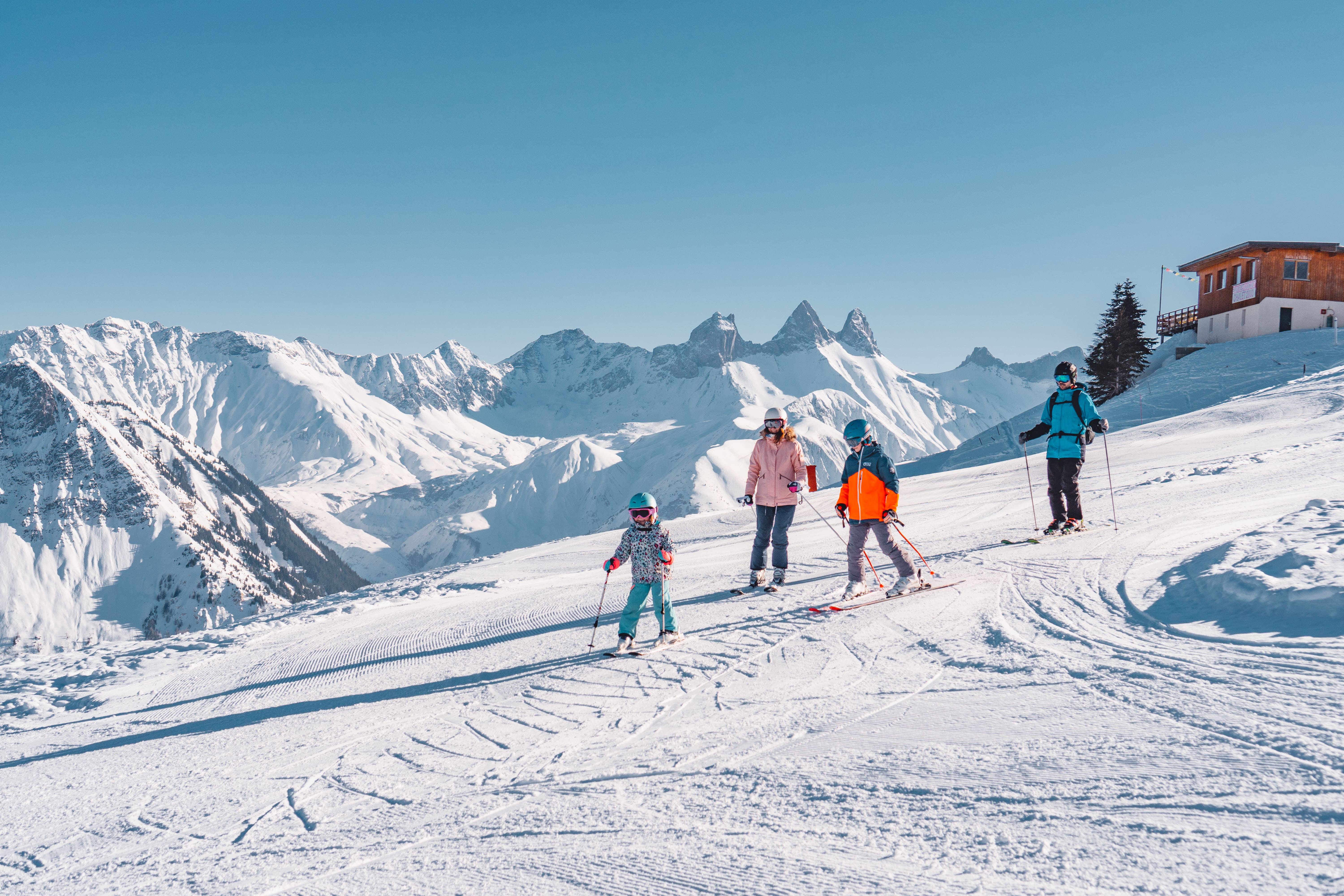 2 enfants et leurs parents qui font du ski après un déjeuner au chalet 2000