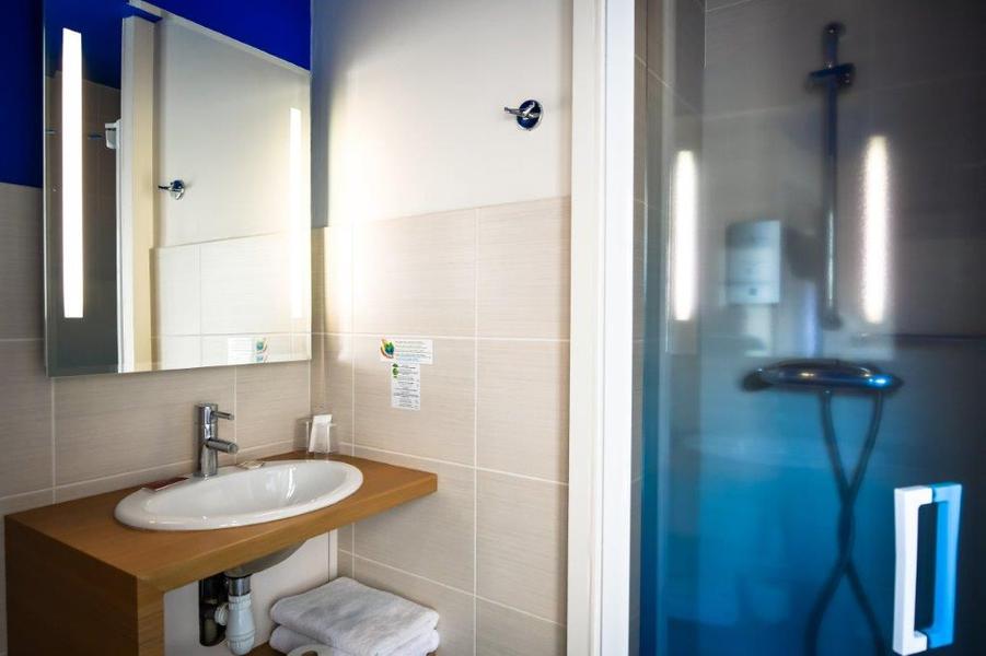 Une Salle d'eau avec douche, lavabo, miroir.