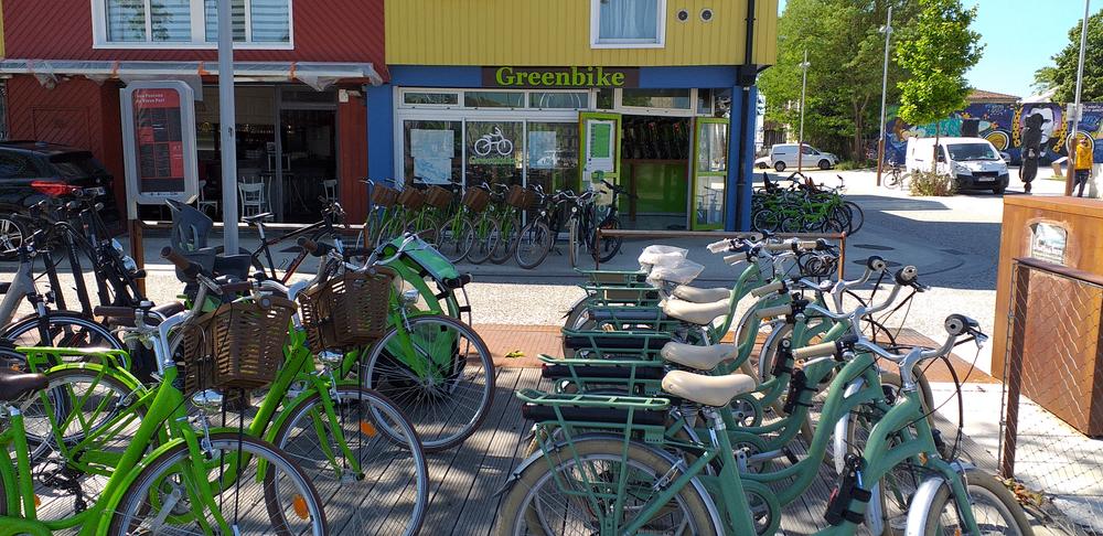 une trentaine de vélos devant le magasin et sur le trottoir en face.