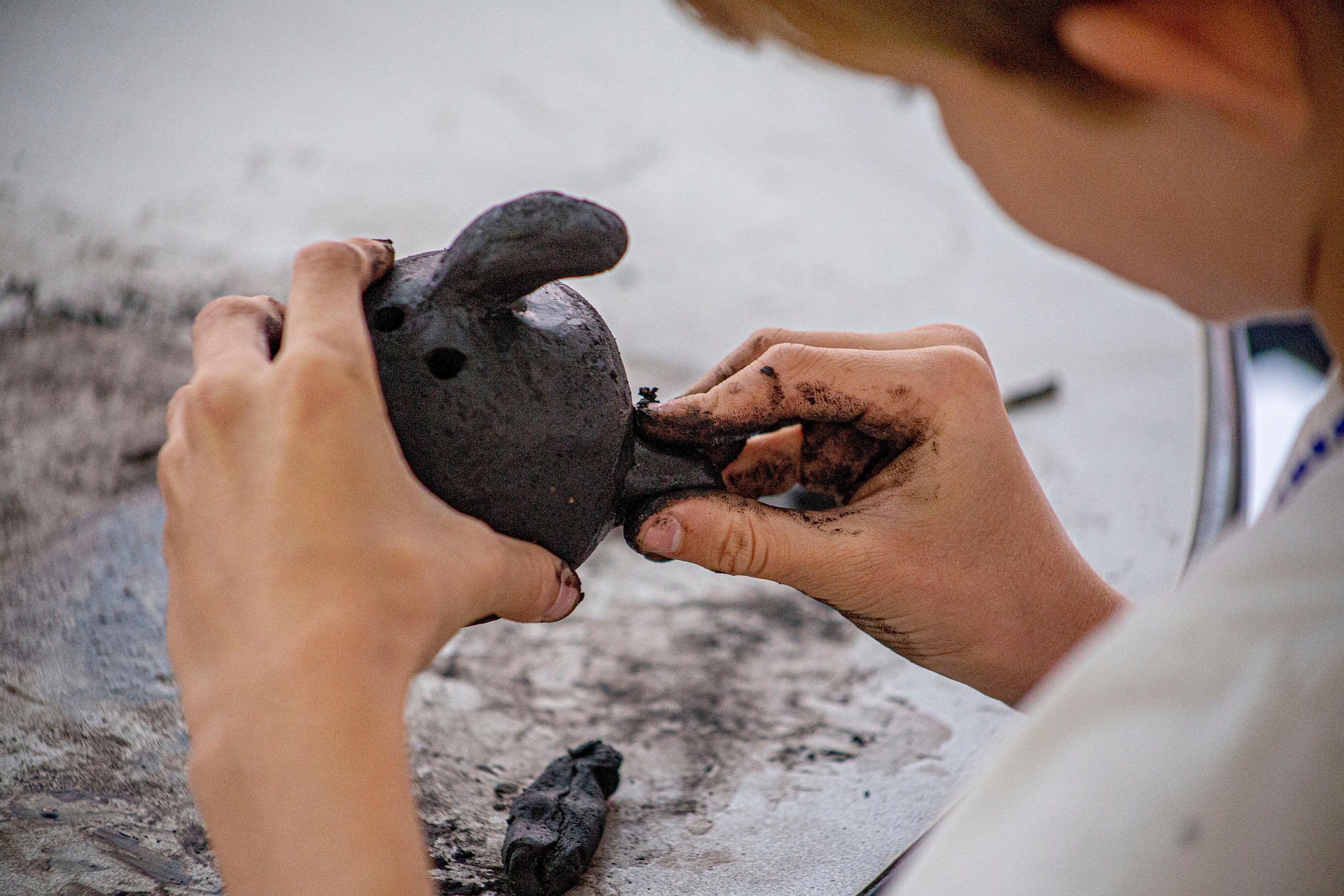 Mains sculptant un personnage en argile