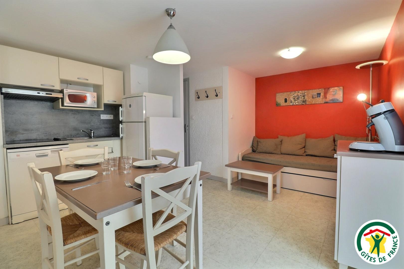 Pièce à vivre, coin cuisine, espace repas, banquette gigogne, TV