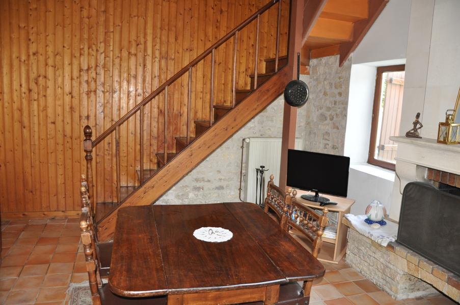 Salon avec table en bois et escalier en bois en arrière plan