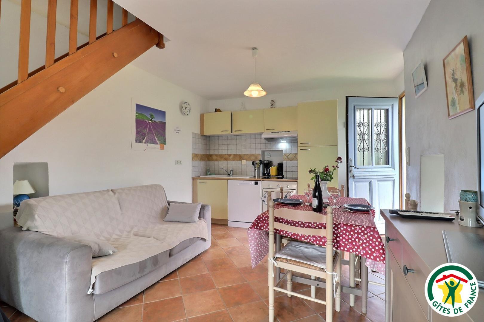 Pièce à vivre avec coin repas, cuisine, canapé, TV. Accès terrasse