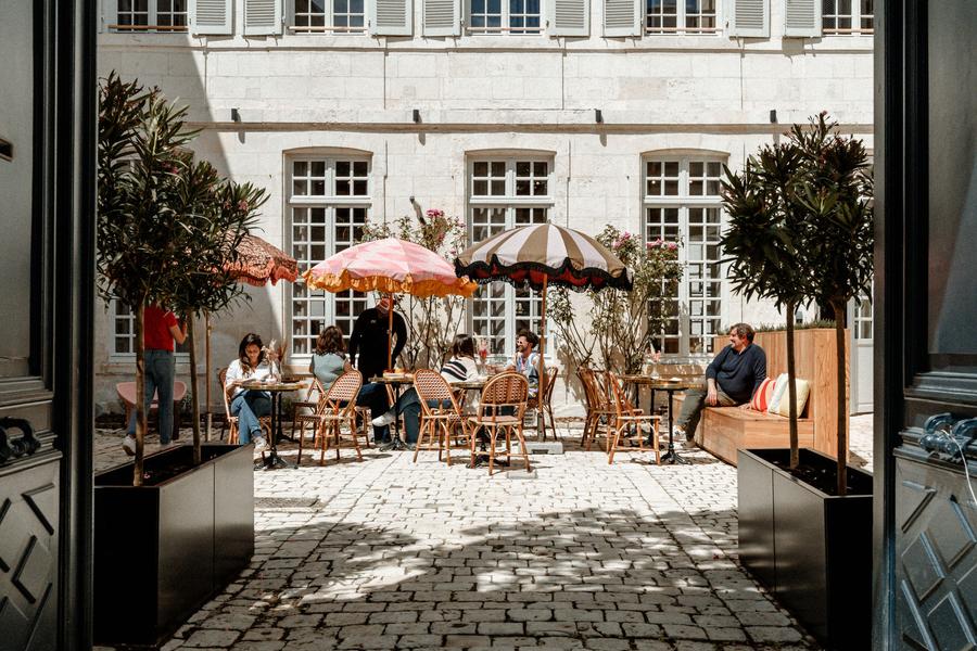 La cour de l'établissement, avec des tables et des parasols.