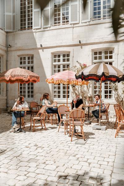 la terrasse dans la cour, avec des tables et des parasols.