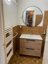 Salle d'eau avec douche, évier, miroir, carrelage