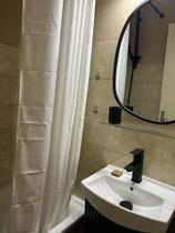 Salle de bains avec baignoire, évier et miroir, carrelage